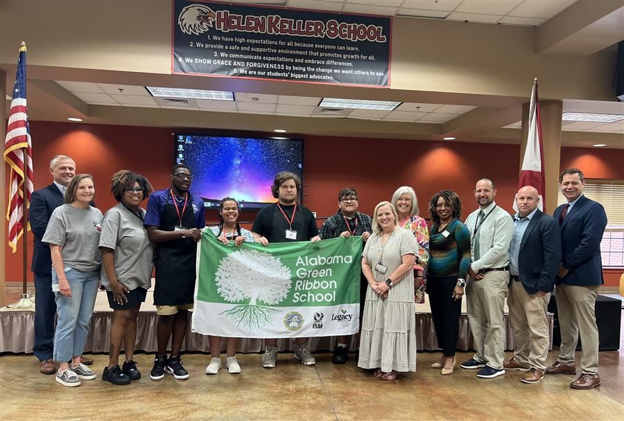  A group of people holding a "Alabama Green Ribbon School" banner at Helen Keller School.
